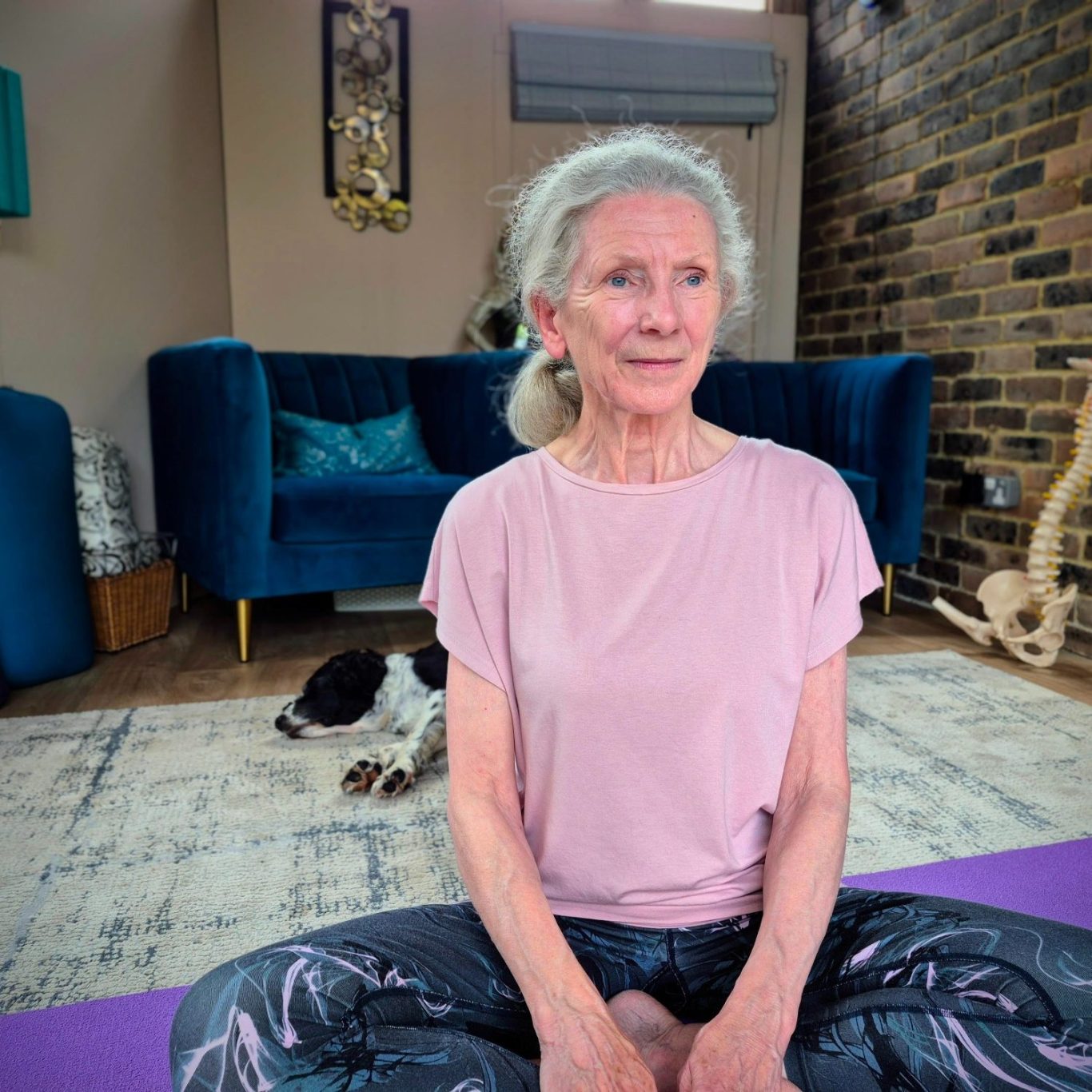 yoga lady claire yoga Elderly woman seated in a yoga pose, smiling, with a dog resting nearby.