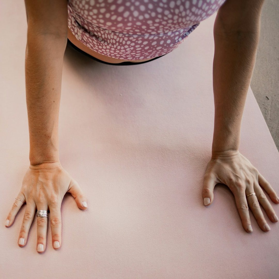 Elderly woman seated in a yoga pose, smiling, with a dog resting nearby.