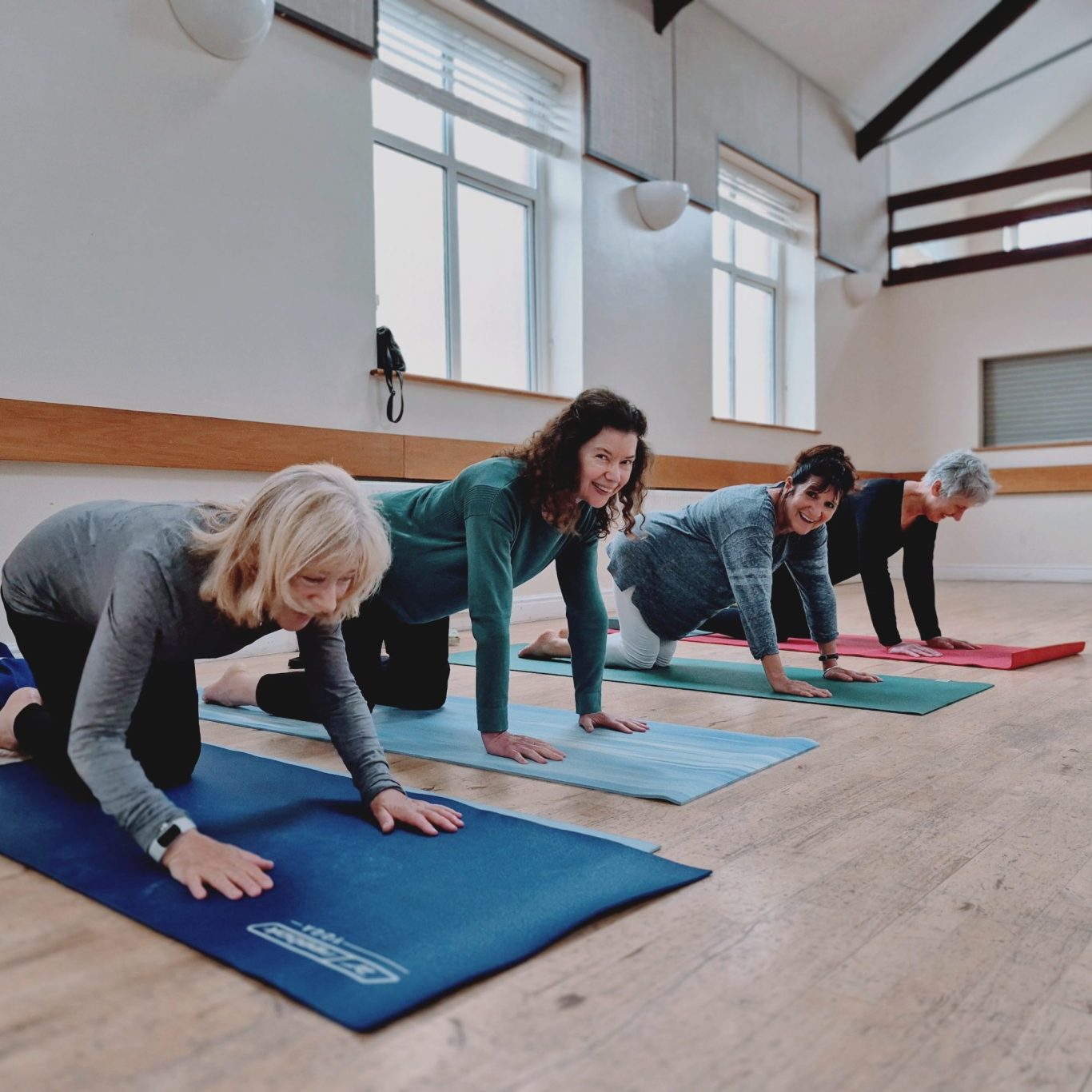 Crowborough Whitehill Centre Four people in yoga poses on mats in a bright, spacious room.