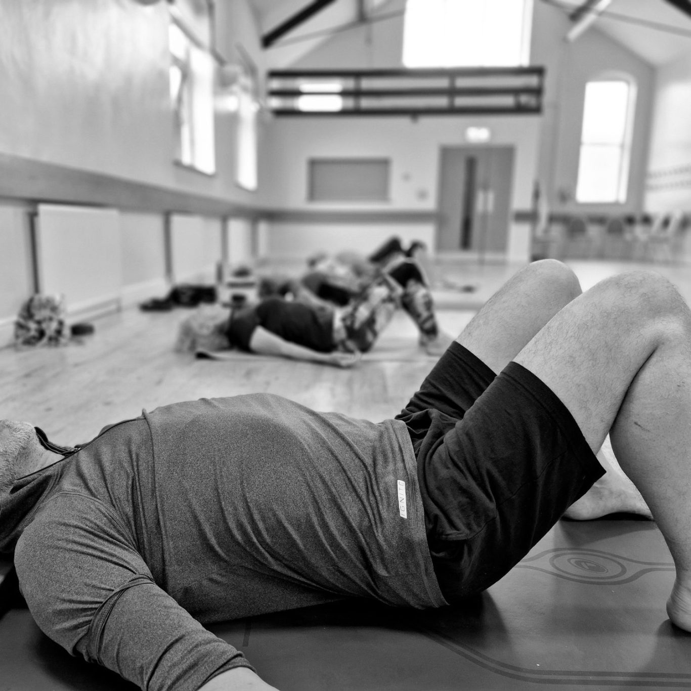 Four people in yoga poses on mats in a bright, spacious room.
