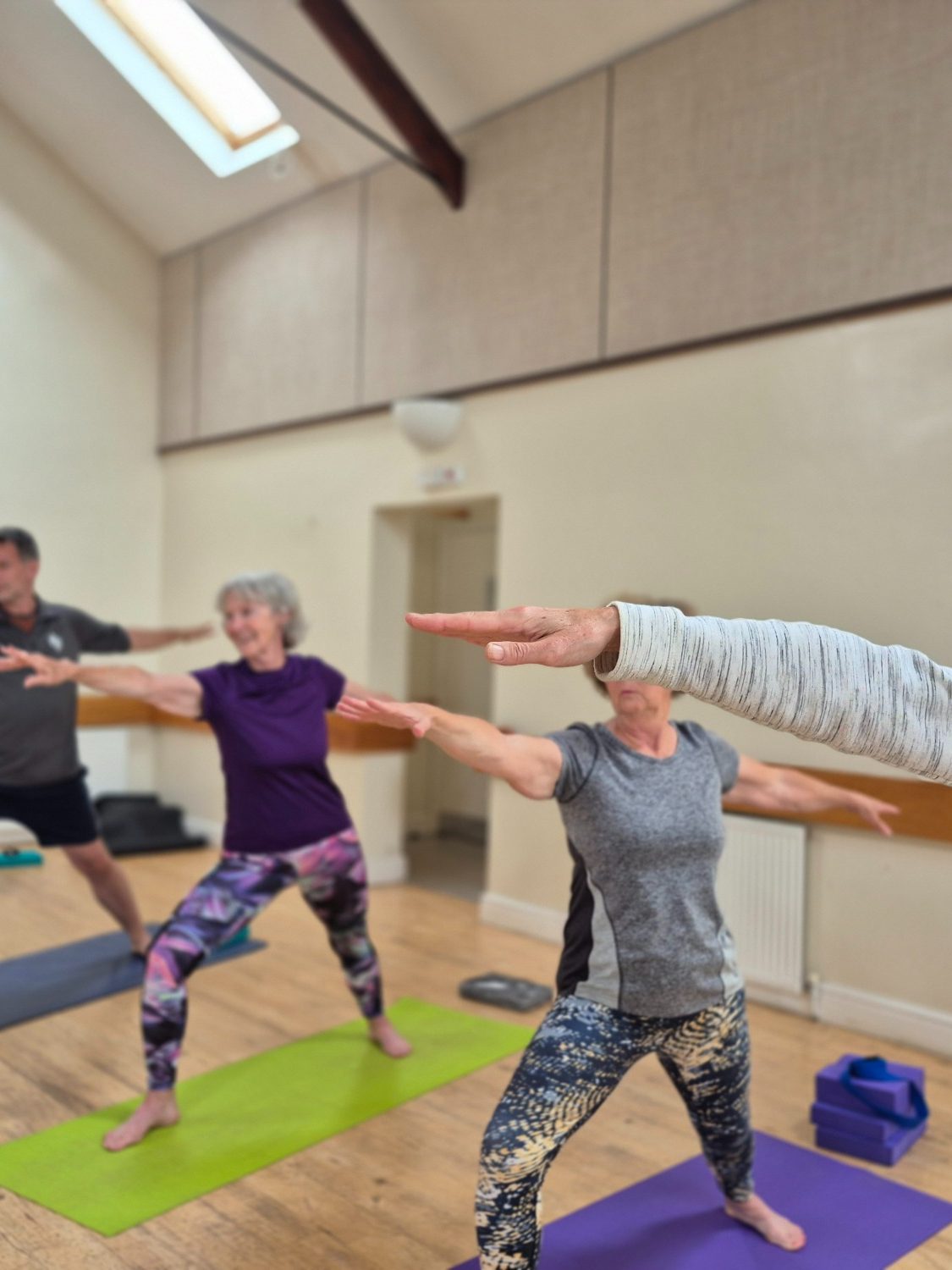 Yoga ladies warrior 2 Group of individuals practising yoga poses in a light, spacious studio.
